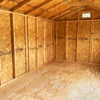 The interior of the 10x20 Ridgeline Shed features unfinished wooden walls and a ceiling made of visible plywood, highlighting the shed's raw wood texture and construction details. The space is empty, allowing for a clear view of these elements, with a small rectangular window located near the top of one wall.