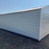 A 12x24 Ridgeline Shed with a gable roof sits on dry grass under a blue sky, another similar shed is partly visible behind it.