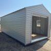 A light gray 12x28 Ridgeline Garage with an open garage door sits on dry grass near a road, trees and another shed behind.
