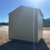 8x8 Ridgeline Shed (Stock #082541439) in beige metal on dry grass by a road, trees and blue sky, bright sunlight glare, available now.