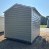 An 8x8 Ridgeline Shed (#062541364) with beige metal exterior, white trim, and peaked roof sits on dry grass beneath a clear sky.