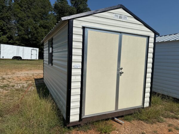8x16 Scratch and Dent Ridgeline Shed, cream metal with black roof and double doors, on grass under blue sky; available now.
