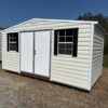 The 8x12 Ridgeline Shed #022041155, with double doors and black-shuttered windows, sits on dry grass under a blue sky.