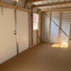 The 8x12 Ridgeline Shed #022041155 features a small interior with plywood floor, exposed studs, metal walls, a white door, and window.
