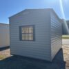 10x16 Hickory Moss garage shed with Black shutters and window on grass, sunny sky, road and trees behind. Available now.