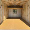 Interior of the 10x14 Estate Garage Shed, Stock #062541367, with exposed wooden beams, window at far end, and clean plywood floor.