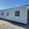 A 10x20 Ridgeline Garage Shed, stock #082541441, with door, three windows, garage entrance, on gravel lot under blue sky.