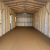 The interior of a 10x20 Ridgeline Garage Shed with unfinished wood, exposed beams, white walls, and natural light from windows.